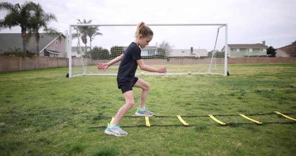 A young athletic girl does the Ickey Shuffle on a speed ladder as part of her warm up before practic