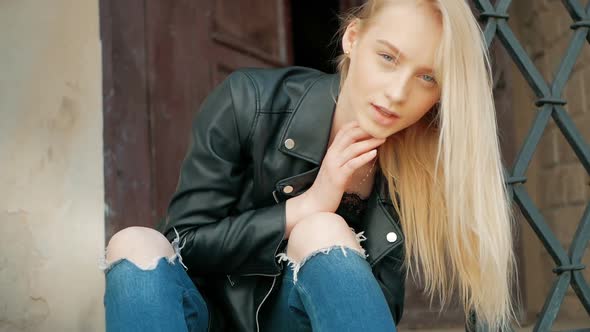 fashion portrait of a beautiful young woman with blue eyes and blonde hair in a leather jacket outdo