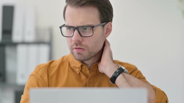 Close Up of Young Man with Laptop Having Neck Pain in Office