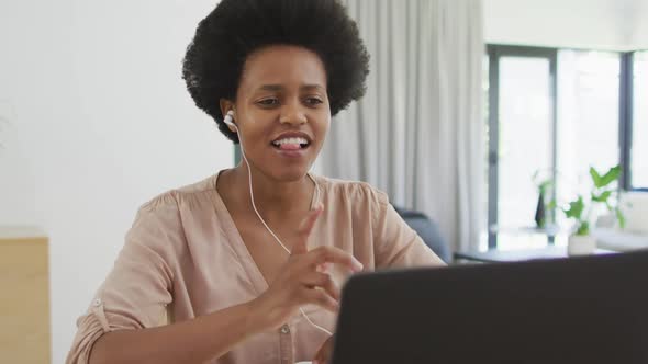 Happy african american woman sitting at table using laptop