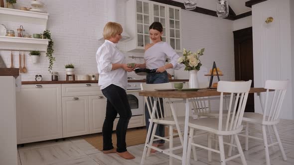 Mother and Daughter Cook Dinner Together and Talk Cheerfully.