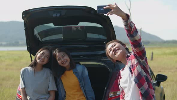 Group of a young teen Asian women selfie-taking photos on mobile phone with friends camping in.