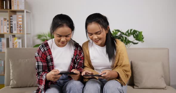 Asian twin girls playing smartphone on phone