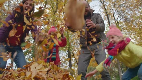 Family Throwing Yellow Leaves in Air