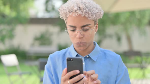 Portrait of Young African Woman Celebrating on Smartphone