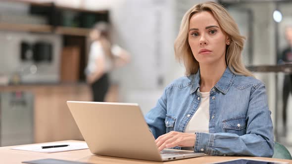 Beautiful Young Casual Woman with Laptop Looking at the Camera 