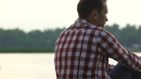 Divorced Man Sitting on River Bank Thinking About Life Injustice Midlife Crisis