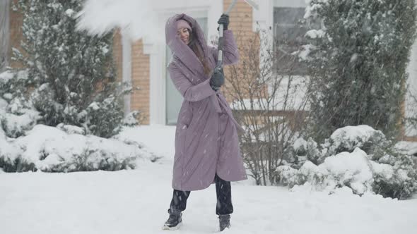 Joyful Slim Charming Woman Cleaning Snow with Shovel and Spinning Laughing Outdoors