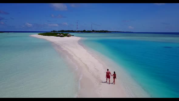 Man and lady happy together on idyllic coast beach journey by aqua blue ocean with clean sandy backg