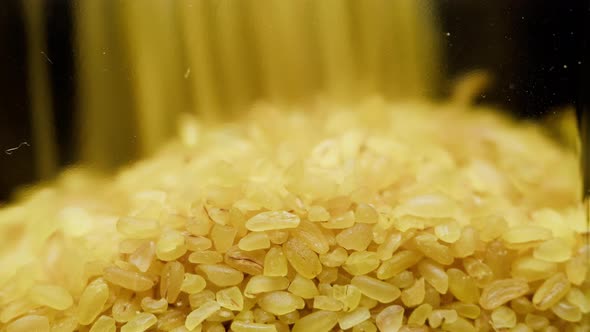 Closeup of Falling Down Bulgur Into Glass Jar on Black Background