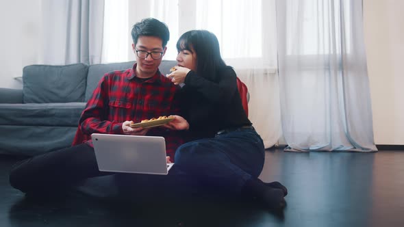 Happy Young Couple Watching Movies on the Laptop or Browsing Social Media with Snack