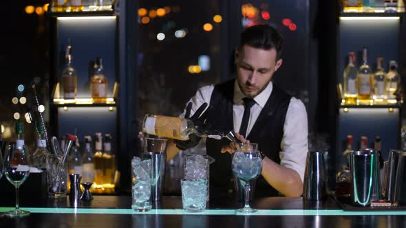 Barman Pouring Liquor From Bottle in Jigger at Bar