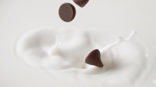 Hershey's Kisses chocolate falling into milk. Slow Motion.