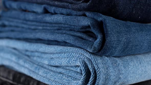 Denim. stack of folded jeans blue, black, light blue, close up. Many pairs of denim trousers