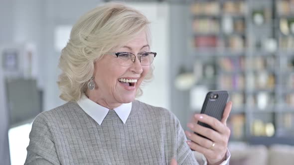 Portrait of Old Woman Celebrating Success on Smartphone