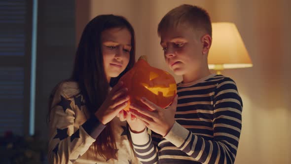 Boy and Girl Playing with Carved Pumpkin at Home on Halloween