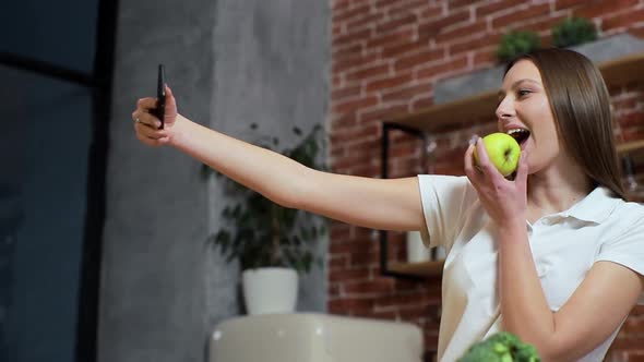 Woman Browsing on Mobile Phone at Home Kitchen. Young Woman Browsing on Smartphone Smiling Happy. A