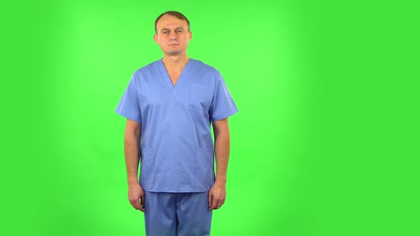 Medical Man Carefully Looks at the Camera in Frustration. Green Screen