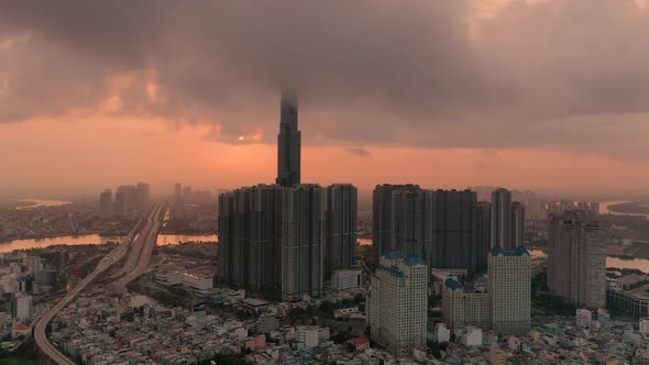 Colorful aerial urban sunrise with high rise building hidden in low cloud. Camera pulls out revealin