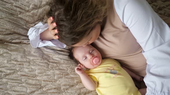 Loving Young Mother Lies Near Sleeping Little Baby Girl