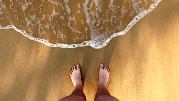 Man's Feet Standing at the Sand Washed By Crystal Clear Ocean Wave