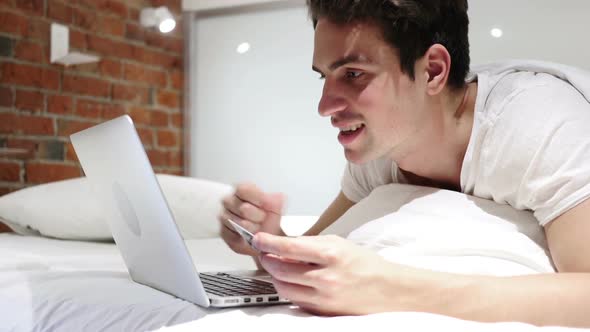 Man in Bed Excited for Successful Online Shopping Transaction