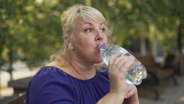 Fat Woman Drinking Water at the Street