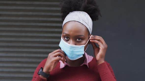 African american putting her face mask on in street