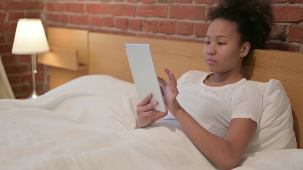 Young African Woman Using Tablet in Bed