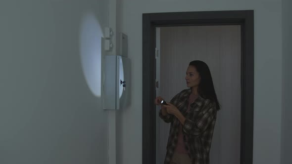 Young Woman Checking Electrical Panel during Power Outage