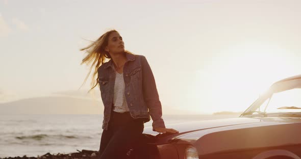 Beautiful woman sitting on the hood of a vintage car