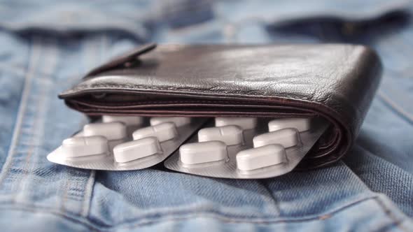 wallet with packs of white pills drops on denim clothes. 