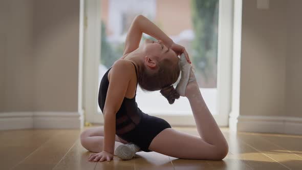 Side View Flexible Teen Gymnast Bending Holding Foot at Head Indoors at Home