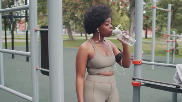 African American Woman Drinking Water during Outdoor Workout