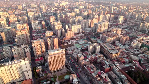 Aerial dolly in of Downtown Santiago crowded neighborhood buildings at golden hour, Chile