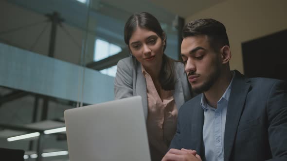 Young Middle Eastern Man Newcomer Study to Work on Laptop at New Job Young Woman Helping Him at