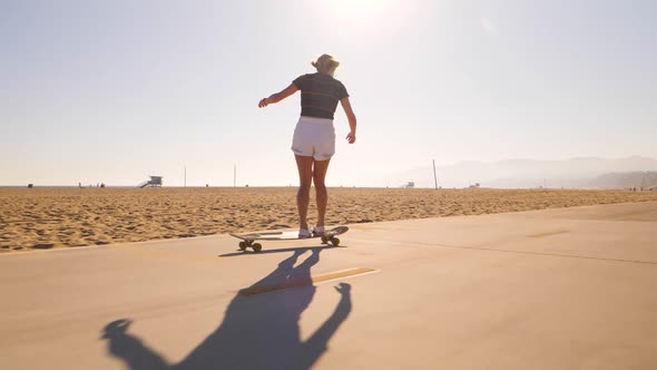 Rear Of A Woman In Skateboard Backlit Bright Sunlight In Desert Skatepark. Low Angle, Wide Shot