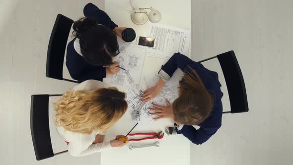 Three Female Engineers Working on Plans at Business Boardroom Table