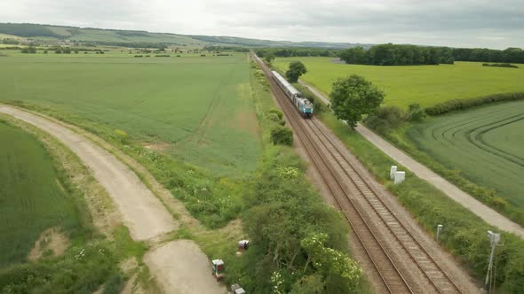 aerial view of train approaching camera on railway track in rural UK countryside