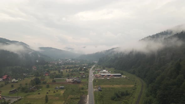 Cars driving on road through valley in Ukraine. Aerial.