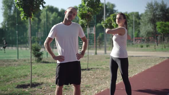 Adult Caucasian Sportive People Warming Up Before Jogging on Running Track. Positive Slim Athletic