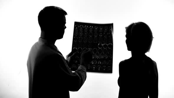 Shadow of Male Doctor Showing to Female Patient Bad Mri Results, Treatment