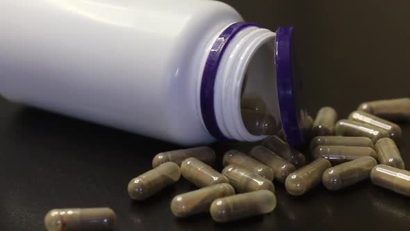 Medicine In Gelatin Capsules. Scattered On The Table. An Overturned Pill Jar With An Open Lid.