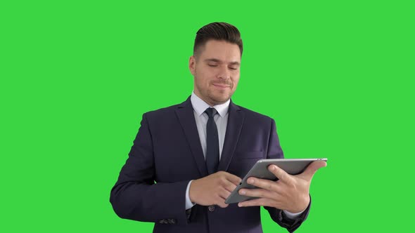 Handsome Man Swiping Pages on Tablet and Smiling To Camera on a Green Screen, Chroma Key