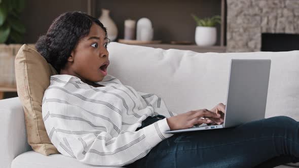 African Girl Freelancer American Biracial Woman Lying on Couch at Home Looking in Laptop Reading