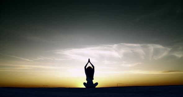 Silhouette of a Girl Doing Yoga Sitting at Sunset