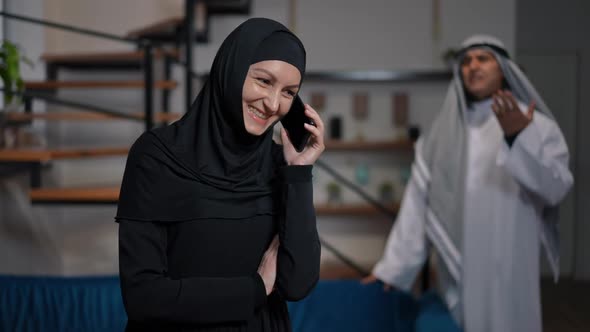 Cheerful Middle Eastern Woman Talking on Phone Smiling Ignoring Unsatisfied Man Talking at