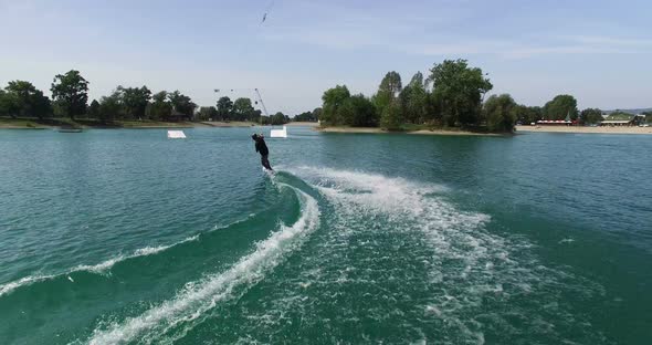 Back view of man jumps over the kicker at wake park