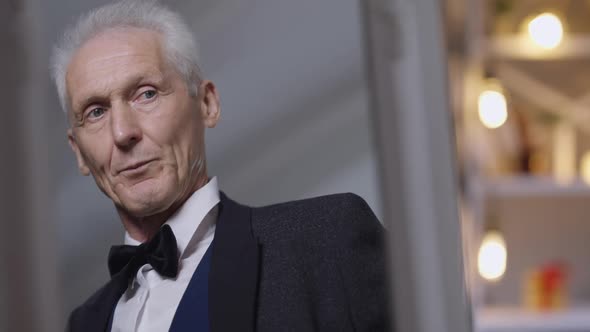 Reflection in Mirror of Confident Handsome Elegant Senior Groom in Wedding Suit and Bow Tie Standing