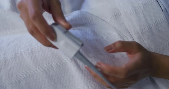 Mixed race female patient lying in bed wearing fingertip pulse oximeter